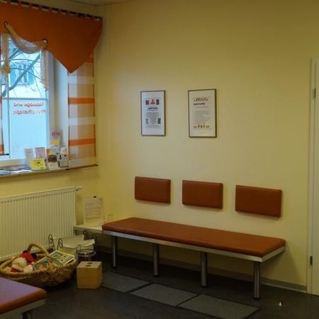 Wartezimmer mit einer Bank, Stühlen und Informationsplakaten